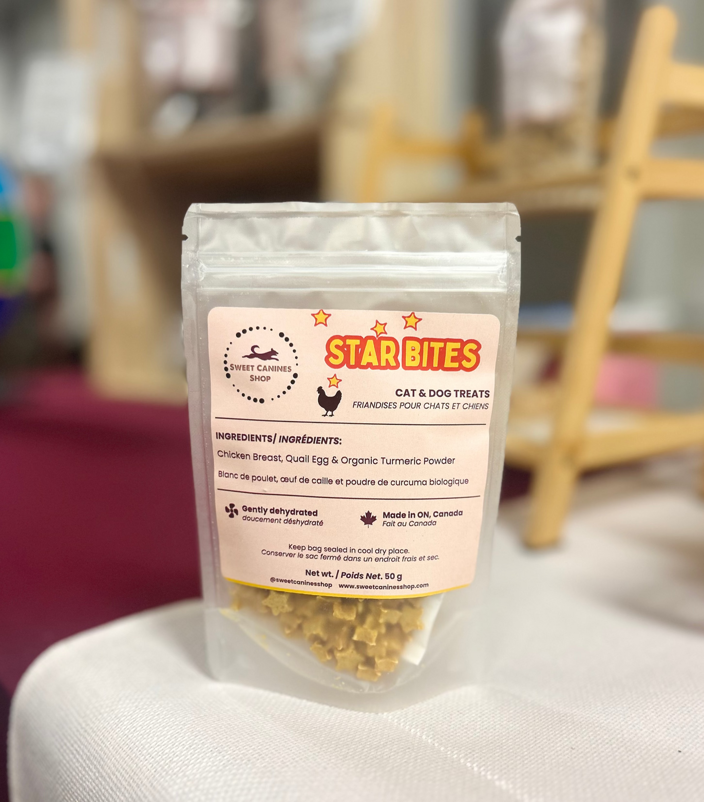 A stand-up pouch of Star Bites Cat & Dog Treats placed on a white surface with a blurred indoor background. The package is clear enough to show the tan treat pieces inside, with a cream label featuring the Star Bites logo and product details.