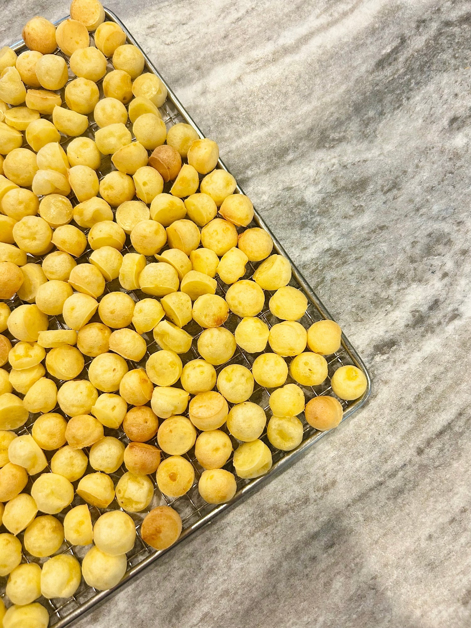 Yellow dog treats on a metal tray with a marble background