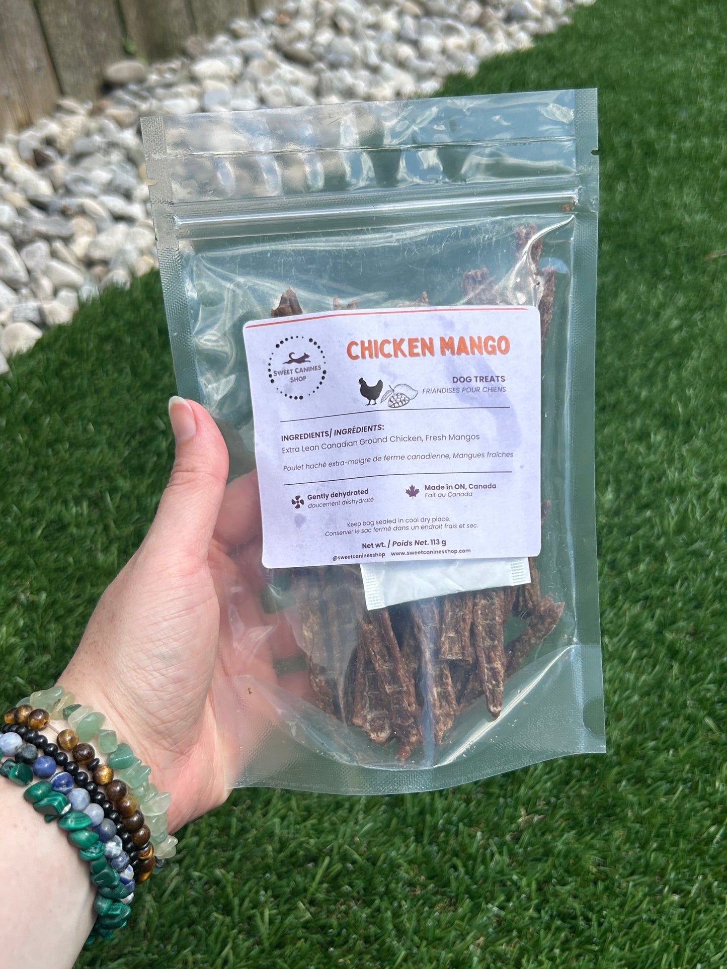 Hand holding a package of Chicken mangos with a grassy background