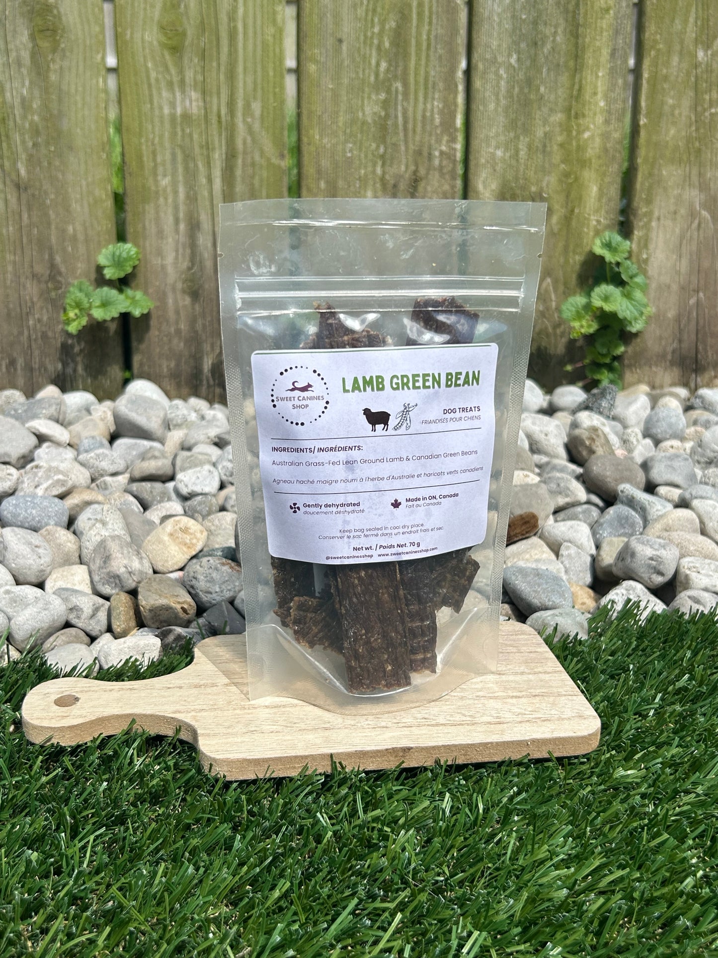Packaged lamb green bean product on a wooden board with a label, outdoors.