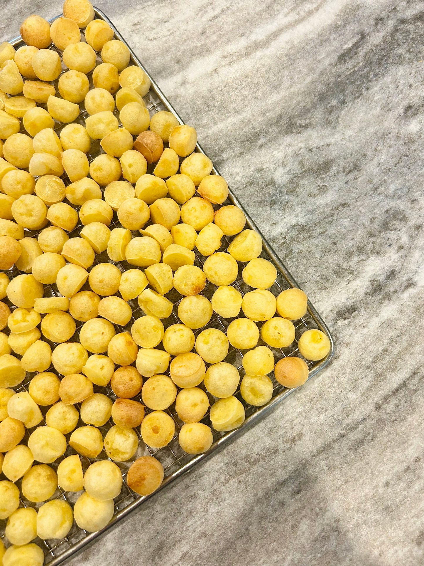 Yellow dog treats on a metal tray with a marble background