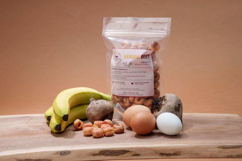 Bananas, eggs, beets and donut shaped dog treats on a cutting board